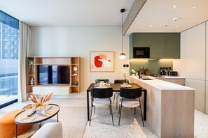 A modern kitchen with a dining area, a large window, and a flat-screen TV.