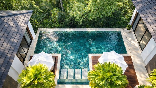 An aerial view of a modern house with a central swimming pool, surrounded by lush greenery and two white umbrellas. - Villa Talun by GORO (Ubud)