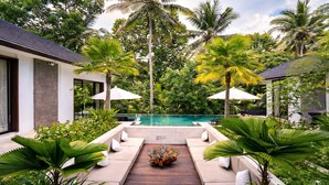 A pool area with a wooden deck, lounge chairs, and umbrellas. - Villa Talun by GORO (Ubud)