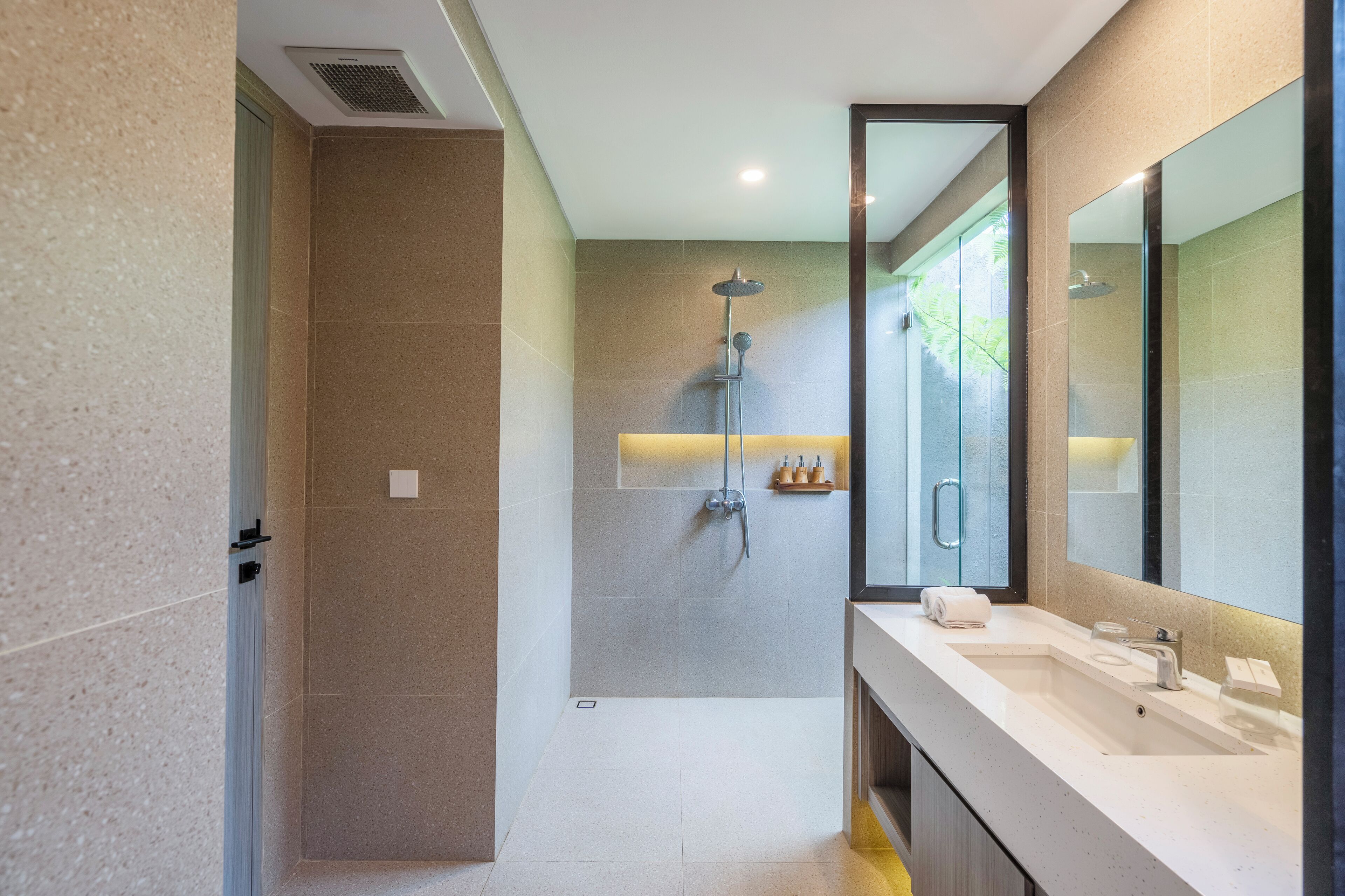 A modern bathroom with a walk-in shower, a large mirror, and a vanity with a sink.