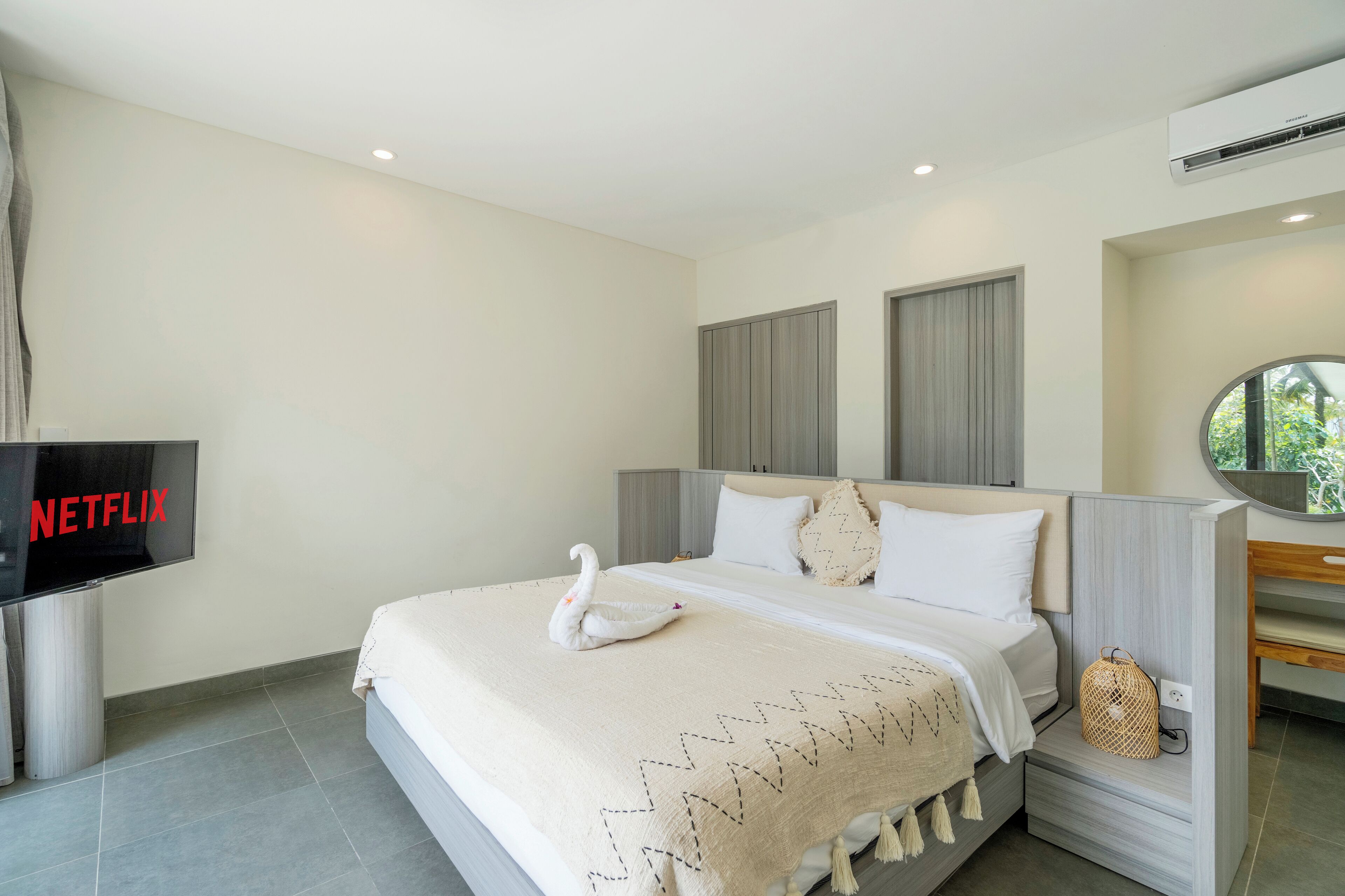 A modern hotel room with a large bed, a TV, and a wall-mounted air conditioner.