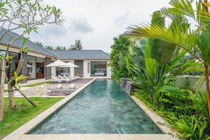 Una piscina al aire libre, sombrillas, tumbonas