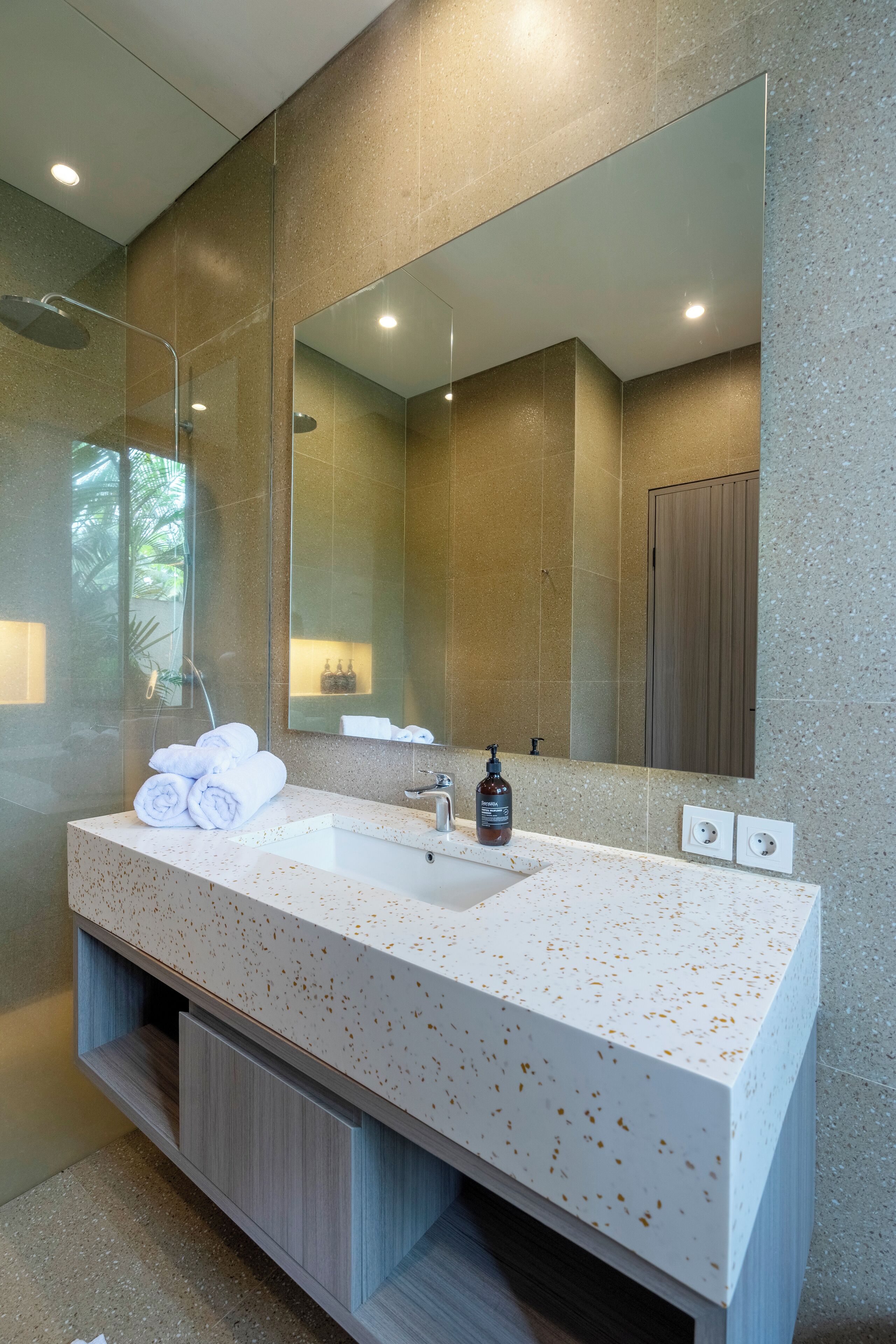 Un baño moderno con un espejo grande, un lavabo blanco y una zona de ducha.