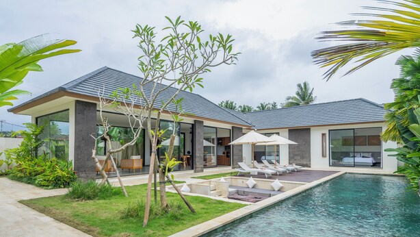 Une maison moderne dotée d’une piscine, d’un espace salon extérieur et d’une végétation luxuriante.