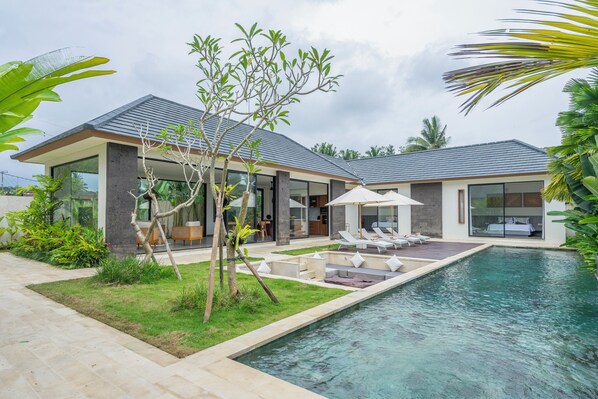 Una piscina al aire libre, sombrillas, sillones reclinables de piscina