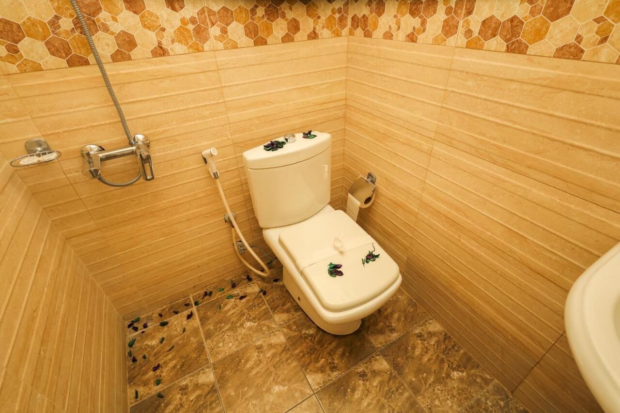 Een badkamer met toilet, douche en betegelde wanden.