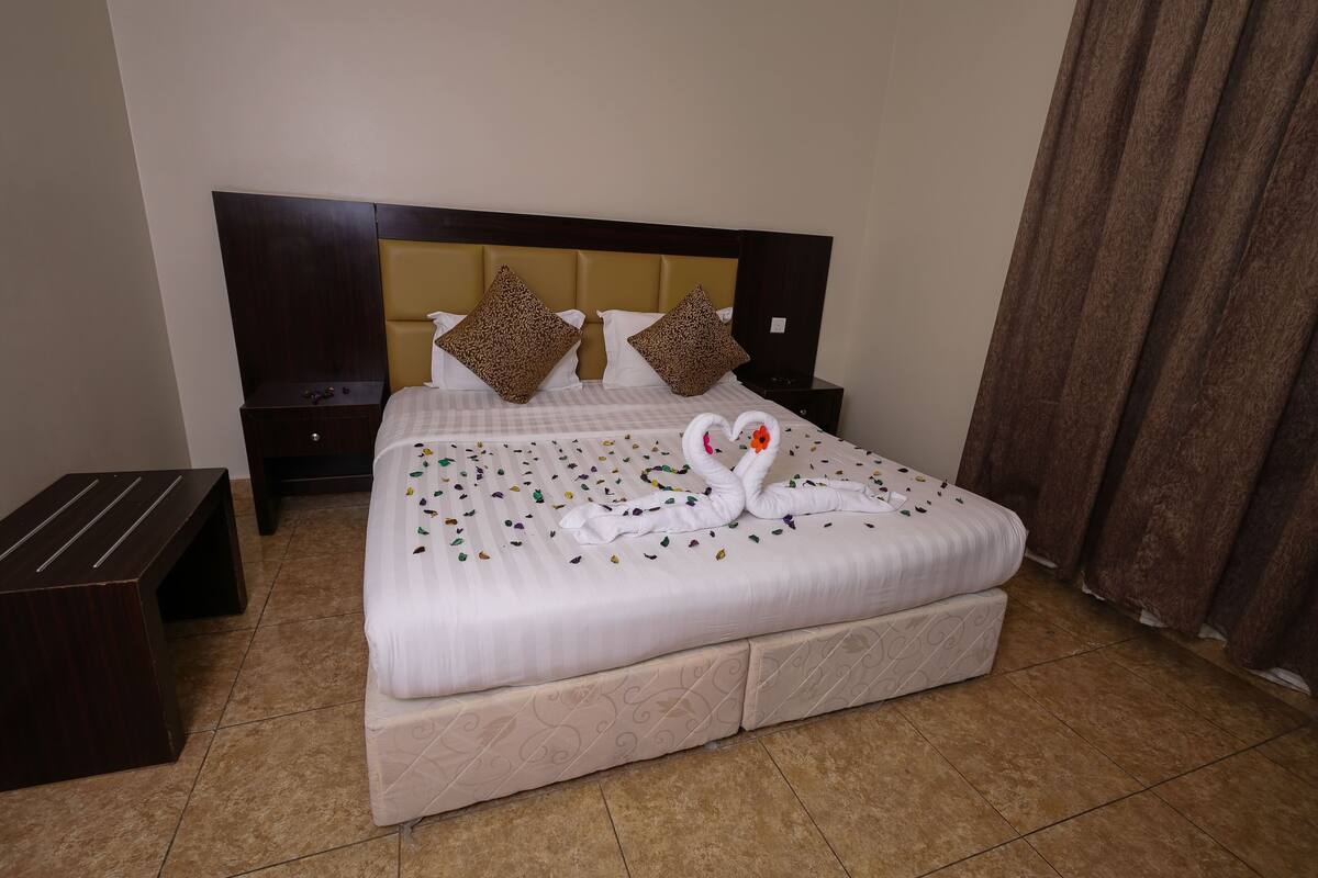 A neatly made bed with a white comforter and decorative swan pillows.