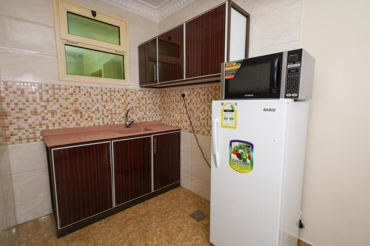 A compact kitchen with a microwave, refrigerator, and wooden cabinets.