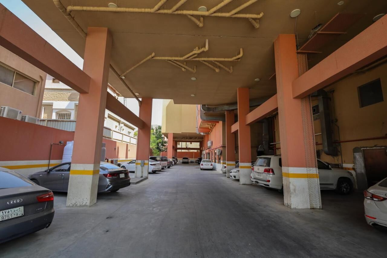 A parking garage with multiple levels and columns, featuring several parked cars.