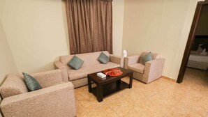 A living room with beige sofas, a dark wooden coffee table, and a brown curtain. - lina 2 (Dammam)