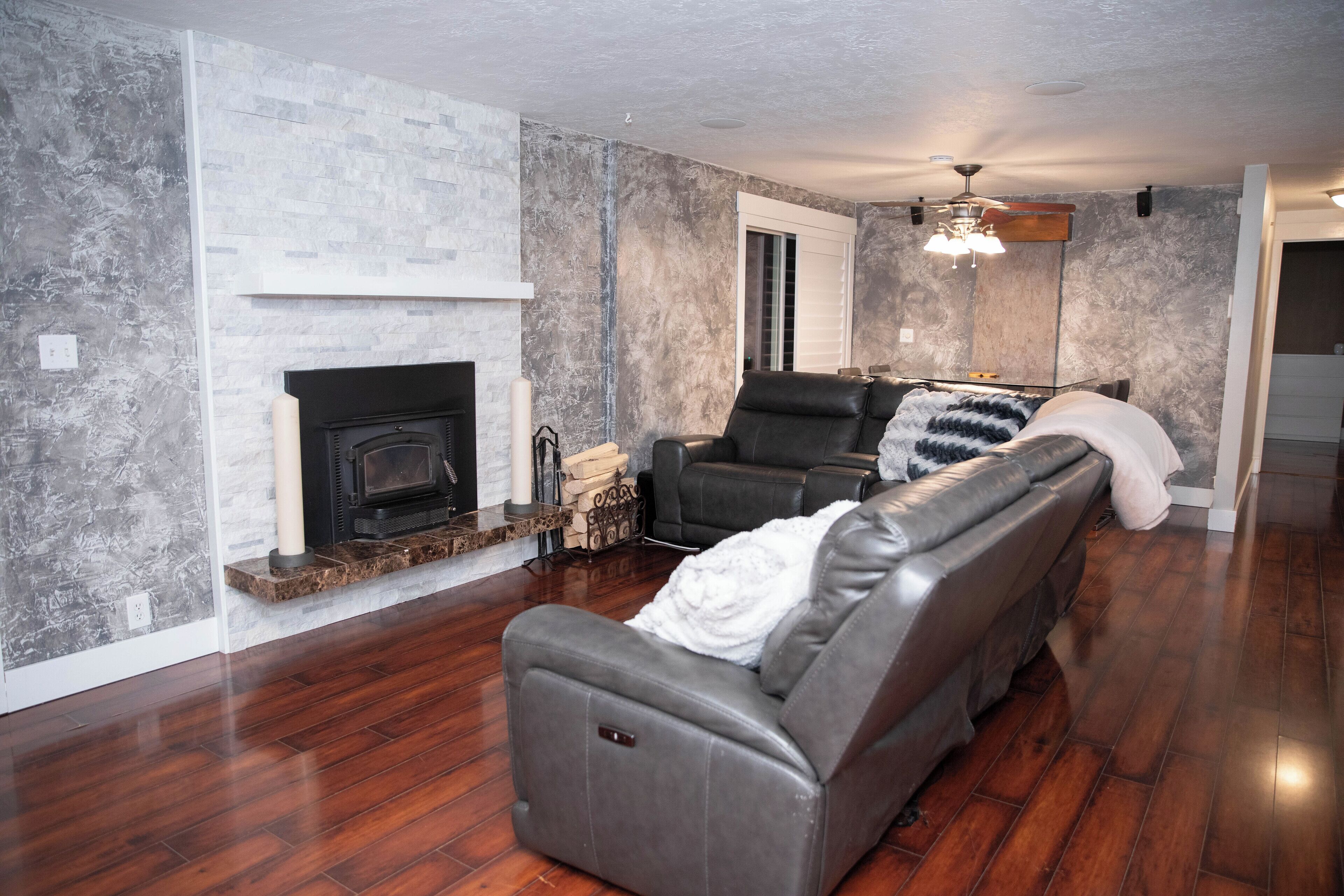 A living room with a fireplace, leather seating, and a stone accent wall.