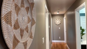 Un pasillo con un tapiz colgando en la pared, un adorno circular y piso de madera.