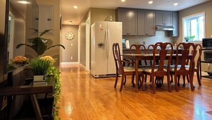 Una cocina moderna con piso de madera, una mesa de comedor con sillas y muebles empotrados.