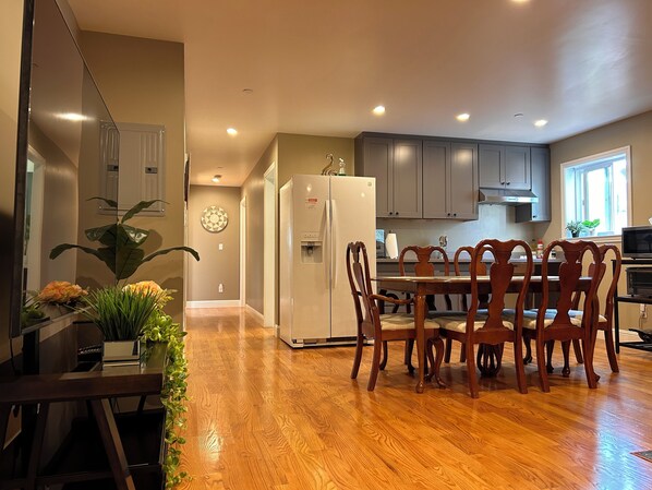 Una cocina moderna con piso de madera, una mesa de comedor con sillas y muebles empotrados.