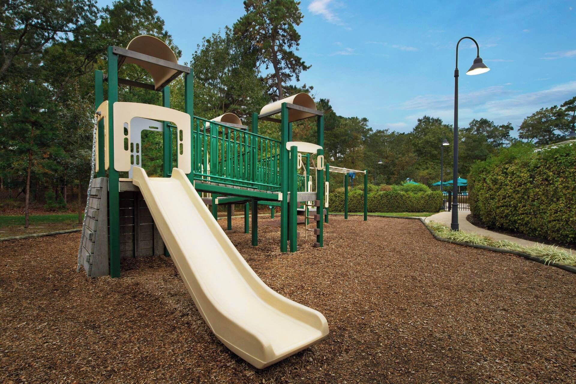 Ein Spielplatz mit Rutsche, Klettergeräten und einer Laterne.