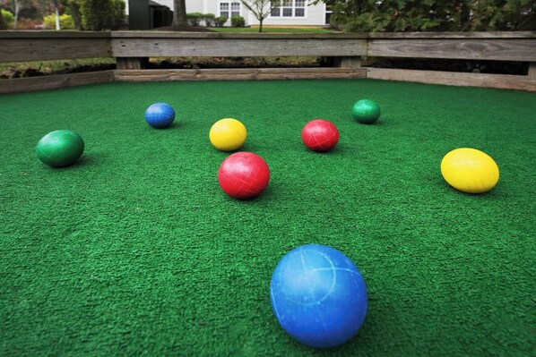 A green artificial turf surface with several colorful balls scattered across it.