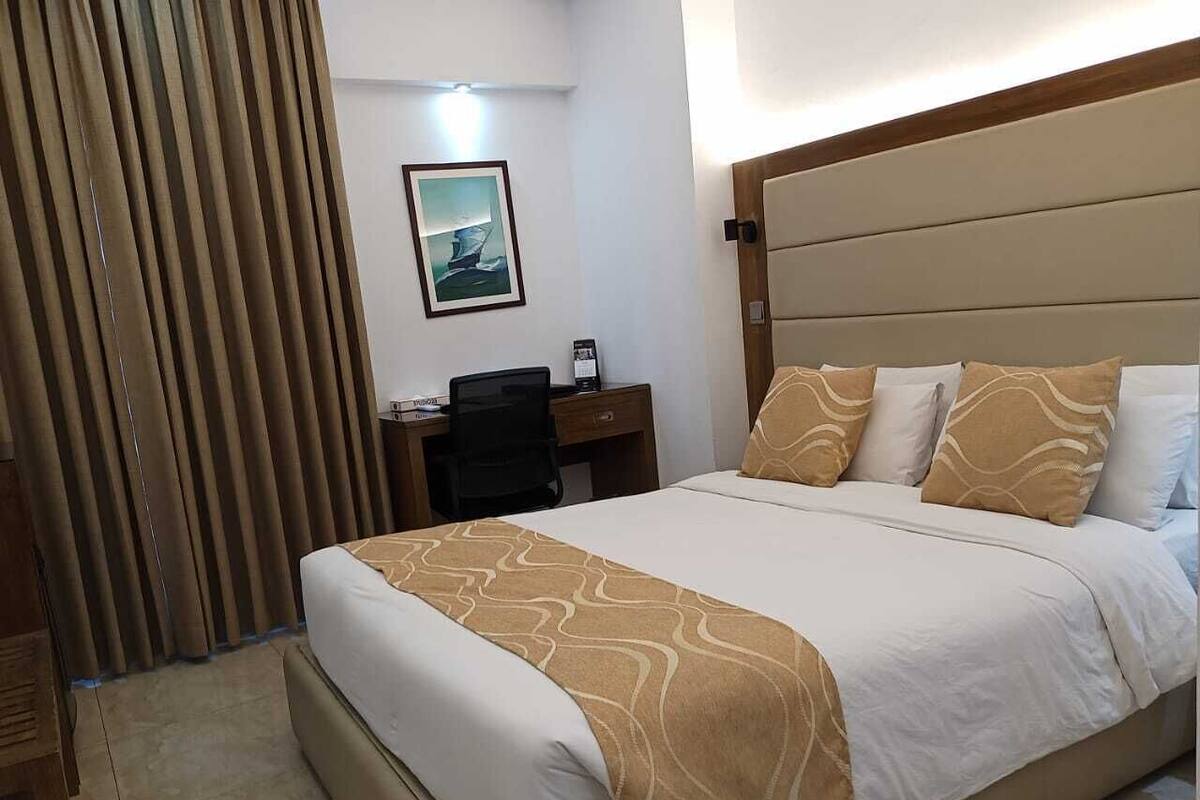A hotel room with a large bed, a desk, and a chair.