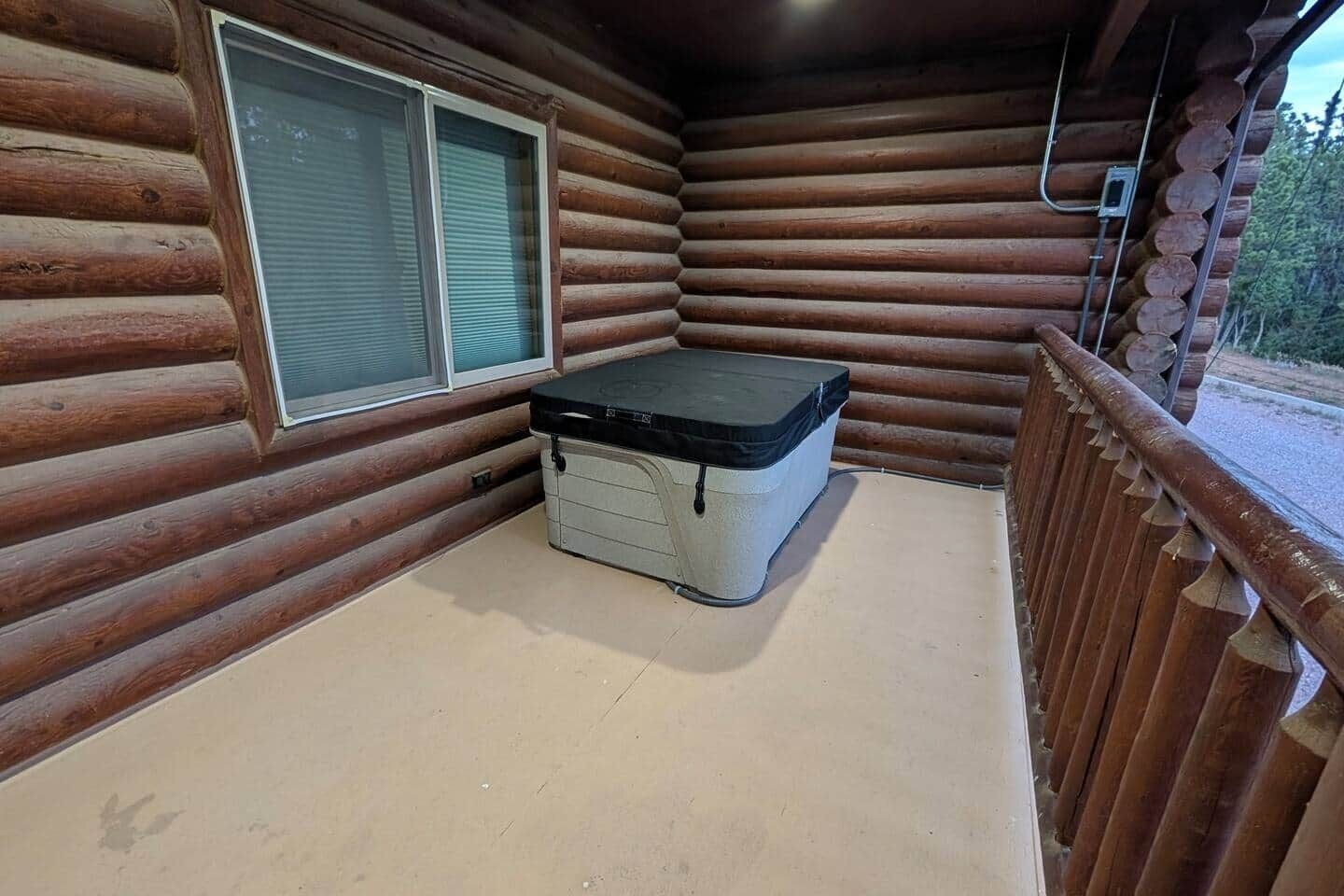Ein Blockhaus-Interieur mit Whirlpool, einem Fenster mit Jalousien und einer Holzdiele.