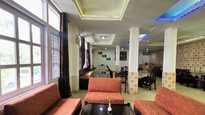 A restaurant with red upholstered seating, a glass coffee table, and a view through large windows. - Hotel Eagle Nest Central Heated  (Dalhousie)