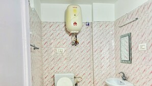 A bathroom with a toilet, bidet, and sink, all with visible plumbing and a water heater on the wall. - Hotel Eagle Nest Central Heated  (Dalhousie)