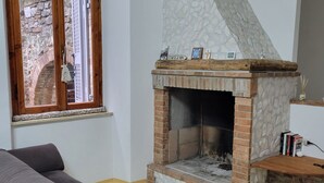 Una sala de estar con chimenea de piedra, un banco de madera y un sofá gris.