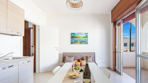 A modern kitchen with a dining area, a painting on the wall, and a view through the window. - 3872 Residence Kalura - Bilo 6 by Barbarhouse (Porto Cesareo)