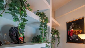 Een kamer met een wit schap waarop decoratieve objecten staan en een Boeddha-schilderij aan de muur.
