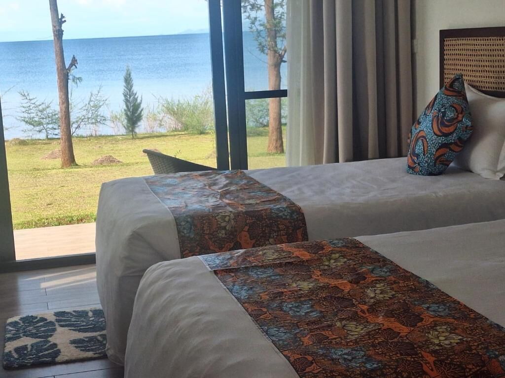 A hotel room with two beds, a view of the ocean, and a large window.