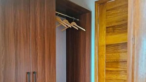 A wooden wardrobe with two doors and a hanging rod. - Eben Lake Kivu Cottages and Villas (Kagano)