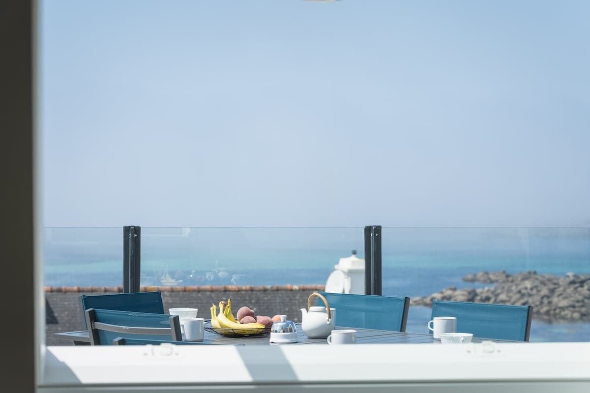 Een tafel met ontbijtartikelen en uitzicht op zee.