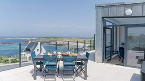 Un balcón con una mesa lista para el desayuno, con vista al mar.