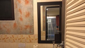 Un baño con lavamanos, espejo, inodoro y cubo de basura.