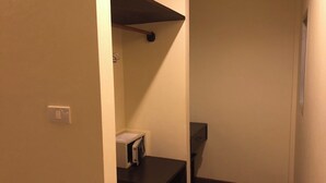 Un pasillo estrecho con un microondas sobre una encimera negra, un estante pequeño y una puerta que da a otra habitación.
