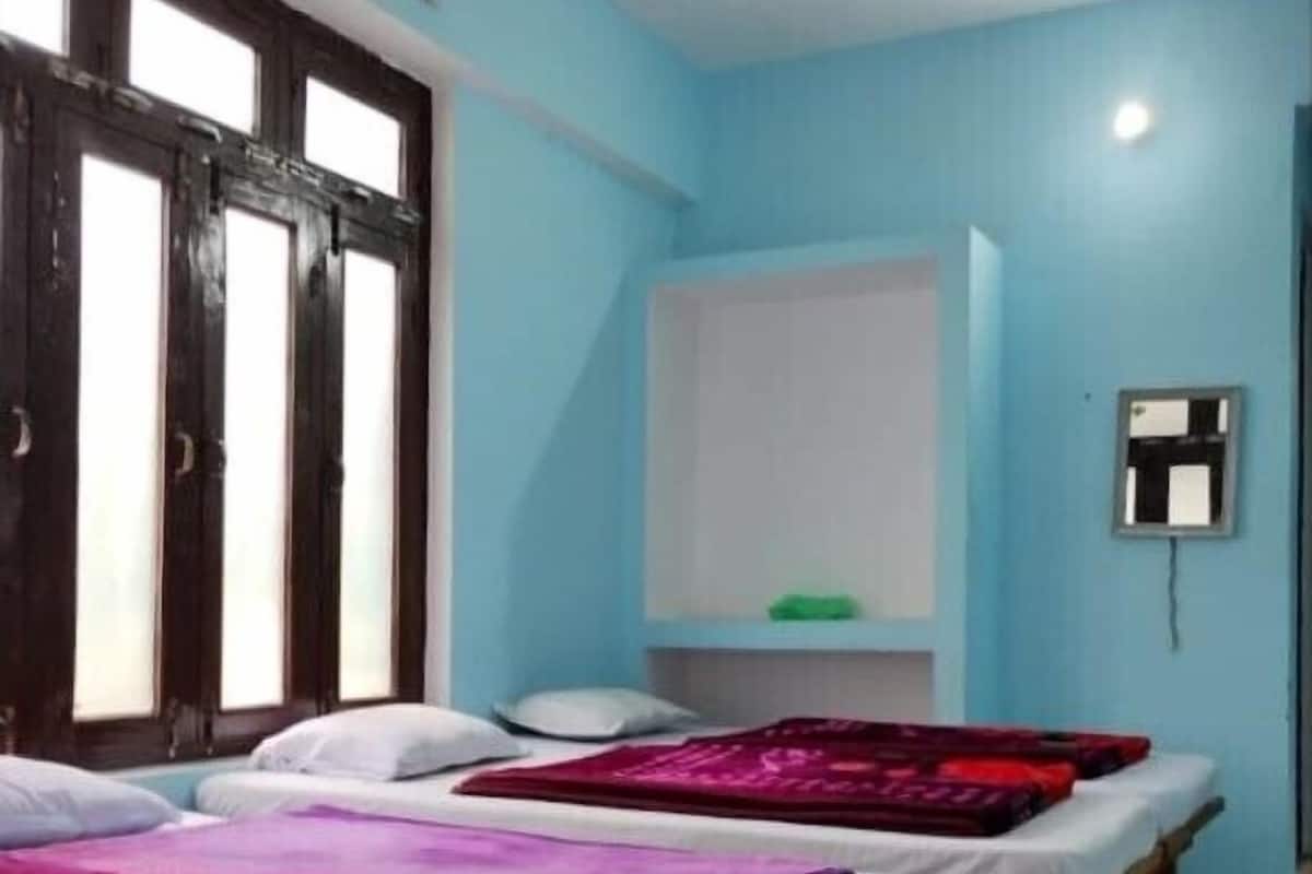 A room with two beds, a window, and a wall-mounted air conditioning unit.