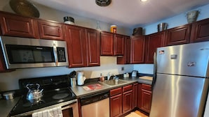 A modern kitchen with stainless steel appliances, wooden cabinets, and a wooden floor. - Beautiful APT W Office Area 2BR Long Term (Elkins Park)