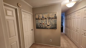 A hallway with beige walls, white doors, and a painting of sailboats on the wall. - Beautiful APT W Office Area 2BR Long Term (Elkins Park)