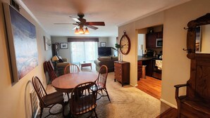 A dining area with a round table and chairs, a ceiling fan, and a kitchen visible through an open doorway. - Beautiful APT W Office Area 2BR Long Term (Elkins Park)