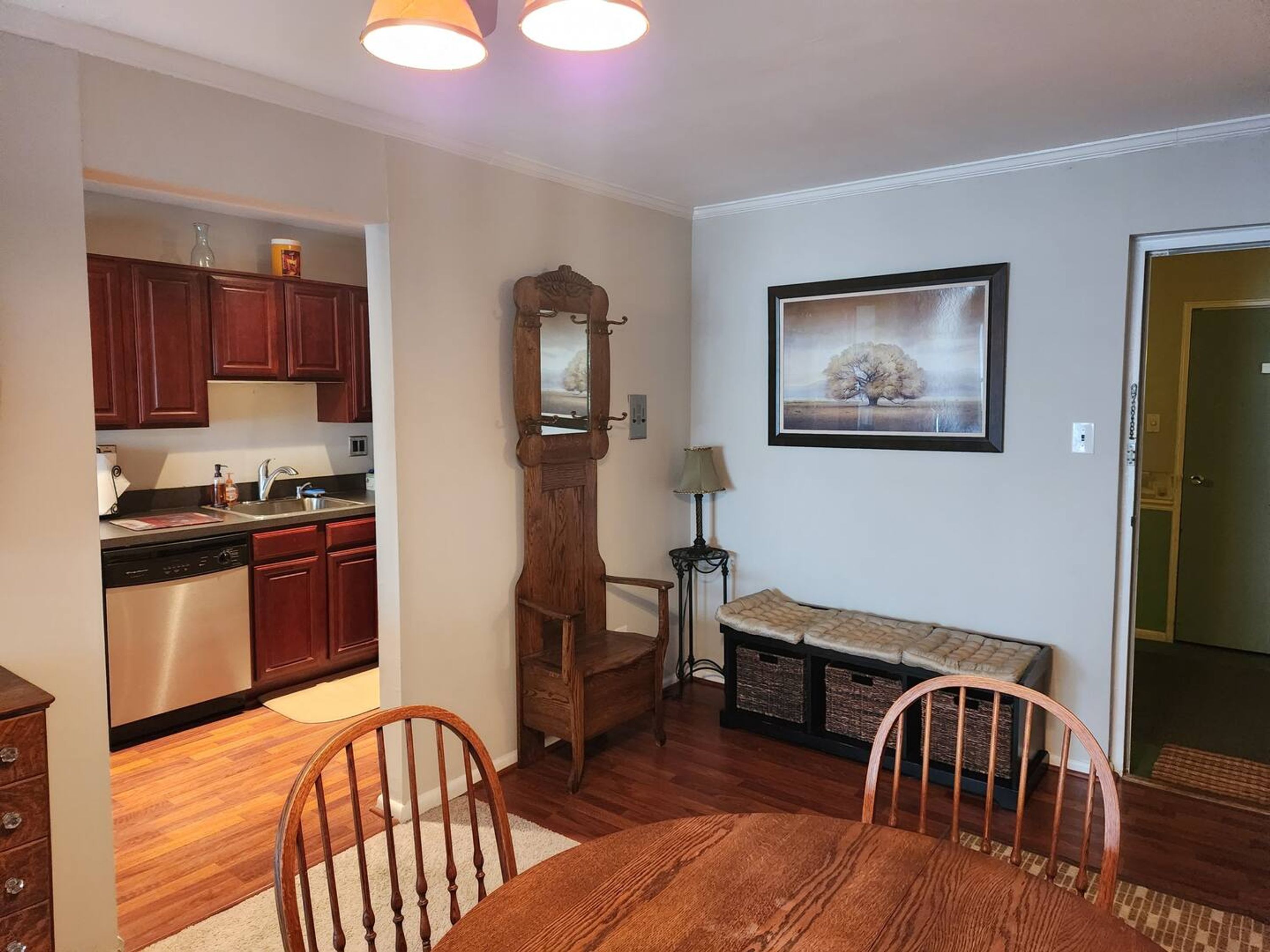 A dining area with a wooden table and chairs, a bench, a mirror, and a framed picture on the wall.