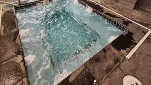Une piscine avec un jacuzzi, une bouée de sauvetage et un panneau sur le mur.