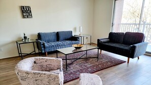 Een zithoek met een blauwe bank, een zwarte bank, een salontafel en twee stoelen met Parijse motieven.