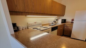 Een moderne keuken met houten kastjes, een granieten aanrechtblad, een witte kookplaat en een koelkast.