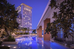 A modern hotel pool area with a clear view of a tall building in the background.