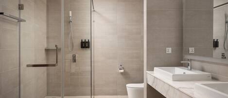 A modern bathroom with a glass-enclosed shower, a white sink, and a large mirror.