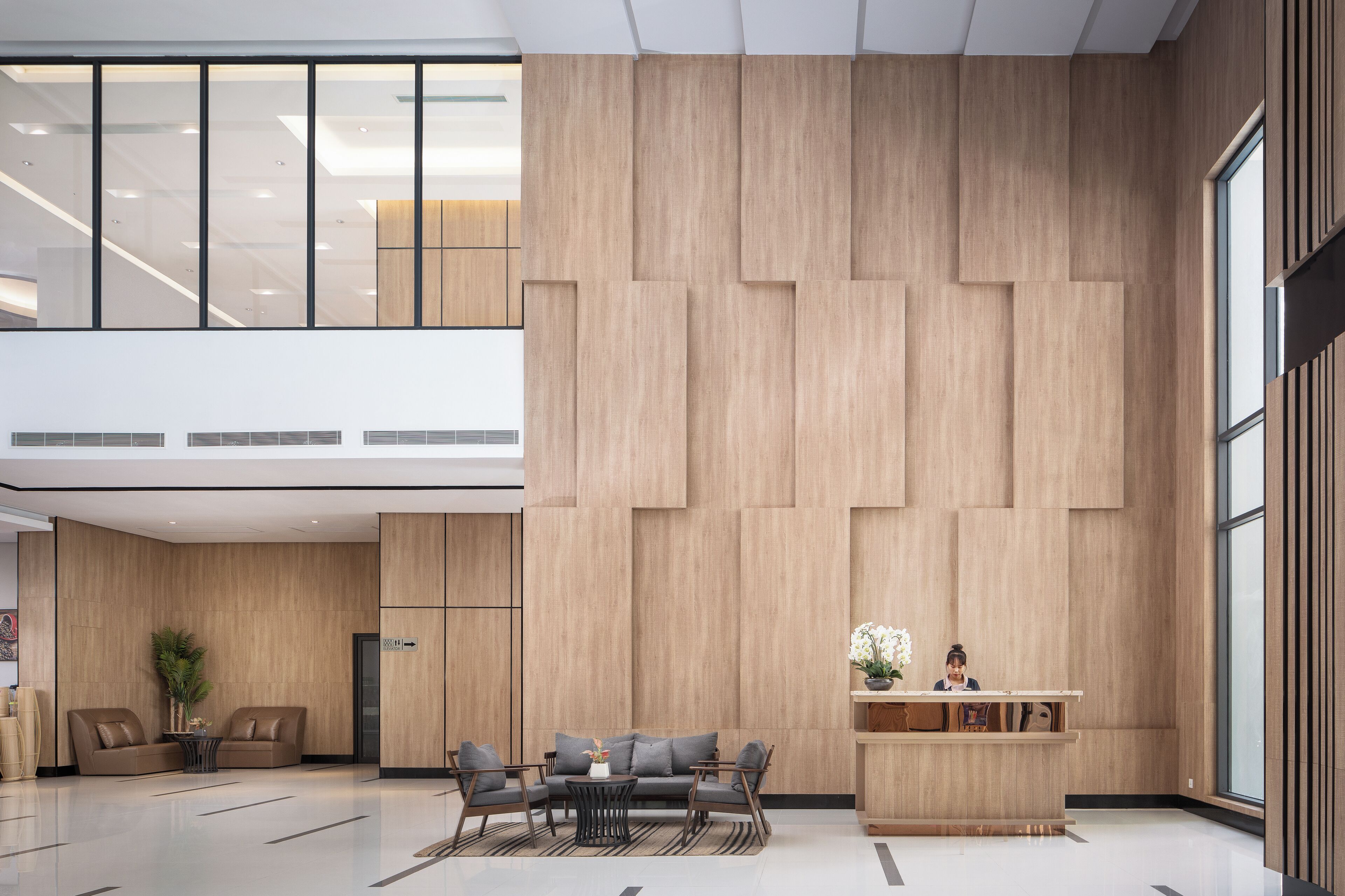 A spacious lobby with a high ceiling, wooden panel walls, and a reception desk.