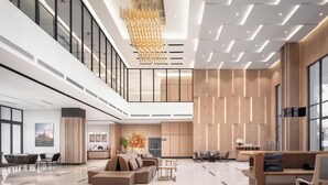 Een ruime lobby met een hoge plafond, moderne verlichtingsarmaturen en een receptiebalie.