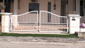 A two-story house with a red-tiled roof, a covered porch with a white railing, and a gated entrance. - SKYN SMART HOME (Ipoh)