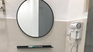 A bathroom with a white sink, black cabinet, and a round mirror. - SKYN SMART HOME (Ipoh)