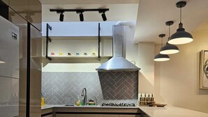 Una cocina moderna con estufa integrada, campana de acero inoxidable e iluminación colgante.