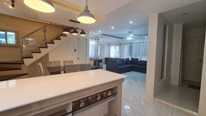 Un espacio habitable moderno con cocina, una mesa de comedor, un sofá y una escalera.
