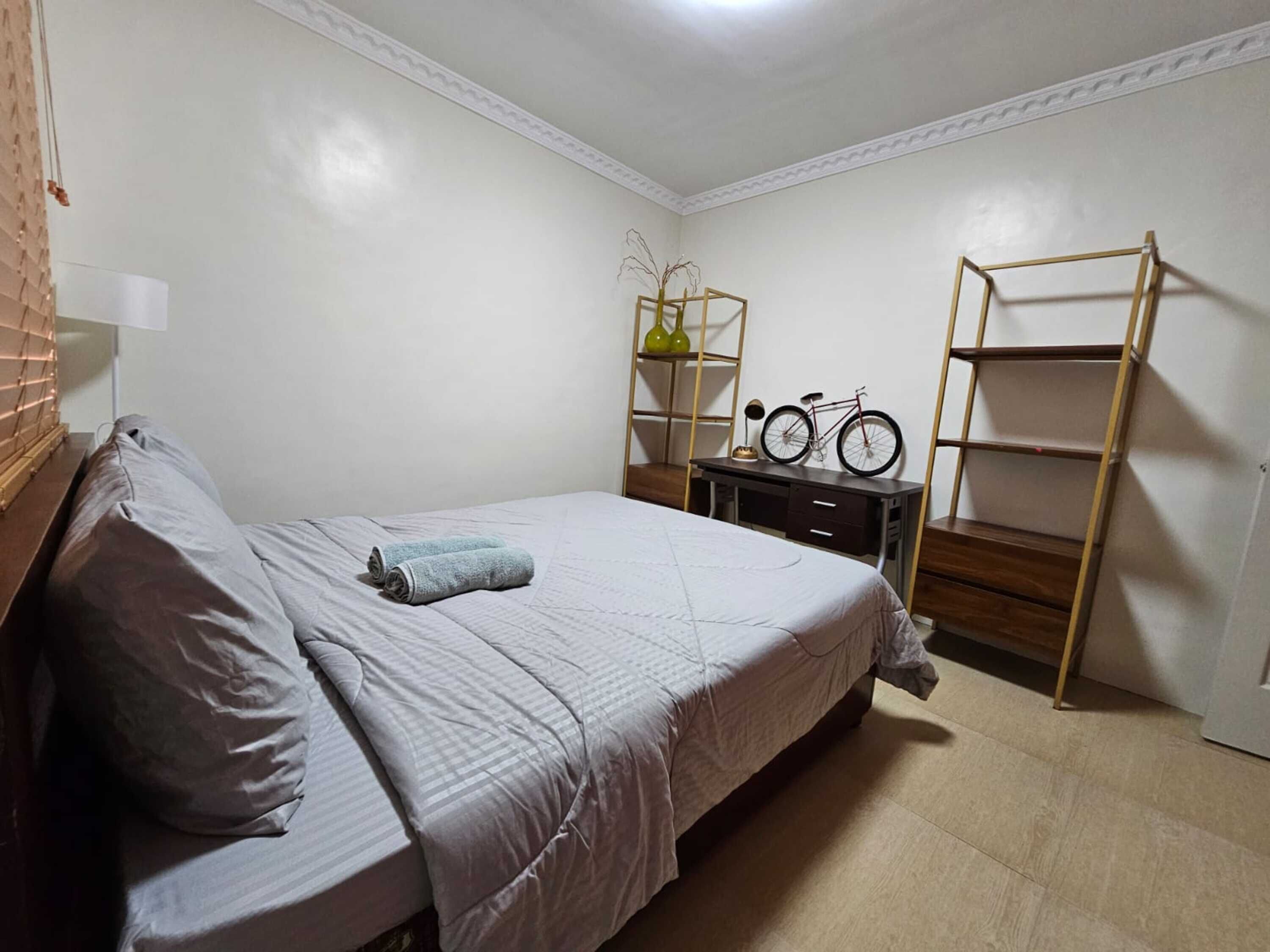 Un dormitorio con cama, escritorio, bicicleta y escalera.